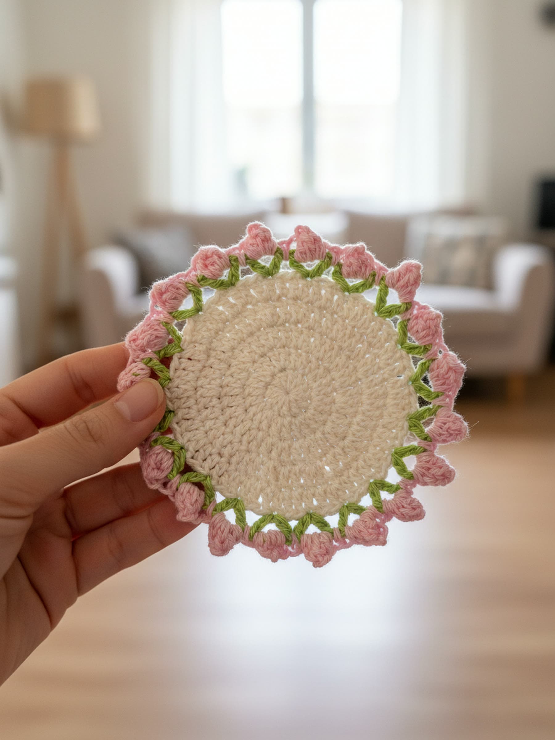 Hand holding a crochet rosebud coaster to show its size